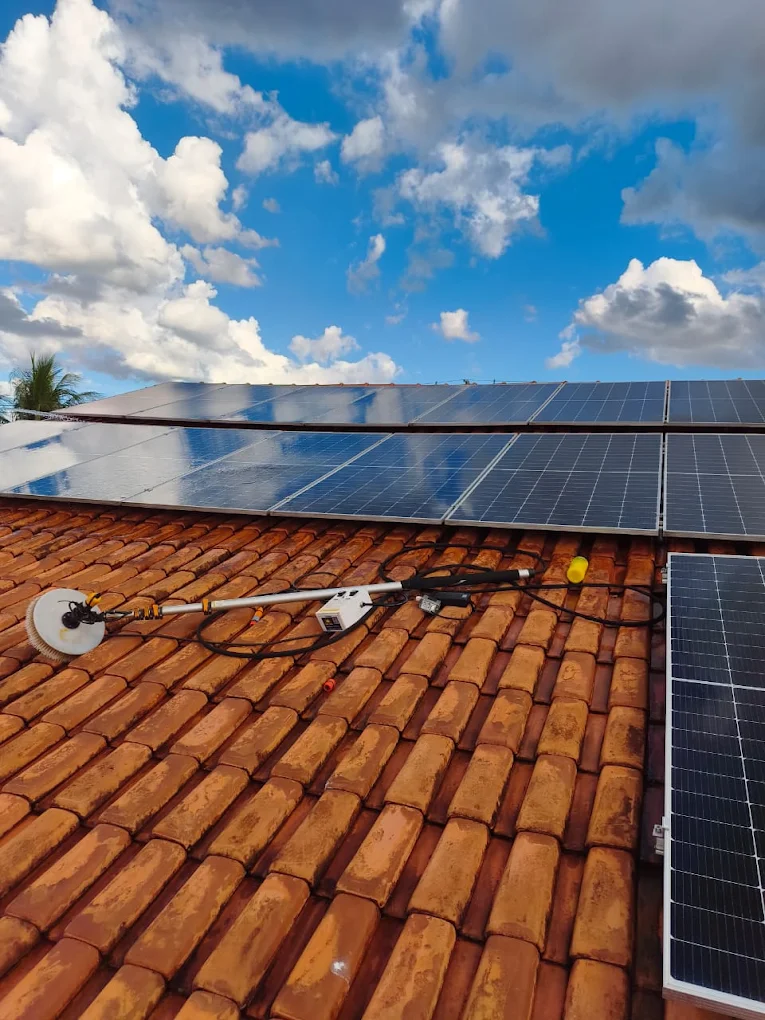 Escova rotativa fazendo limpeza de placas solares sobre telhado de telha cerâmica
